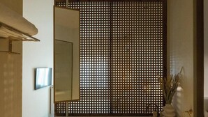 Une salle de bain moderne avec un banc en bois, un grand miroir et un paravent décoratif.