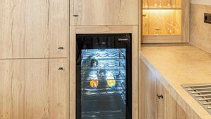 Une cuisine dotée de meubles en bois, d’un réfrigérateur à vin encastré et d’un évier en acier inoxydable.