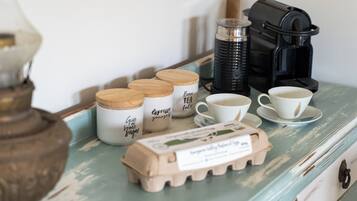 Et bord med kaffemaskine, kopper, krukker og æggebakke.