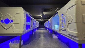 A row of modern, white, capsule-style rooms with blue lighting accents and a central air conditioning vent. - HOTEL GALAXY POD (Koshigaya)