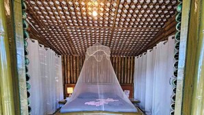 A room with a bed under a net canopy, bamboo flooring, and a ceiling with a lattice design. - Tambayan Rooms & Cottages by SMS Hospitality (Loay)