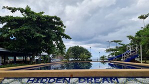 A pool area with a sign reading "Hidden Dream Sunset View Resort". - Tambayan Rooms & Cottages by SMS Hospitality (Loay)