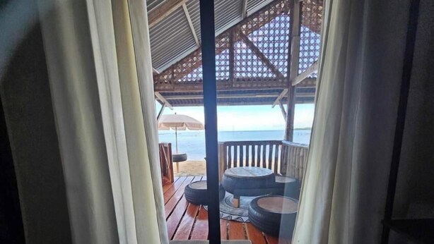 A wooden deck with outdoor seating and a view of the sea. - Tambayan Rooms & Cottages by SMS Hospitality (Loay)