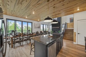 Une cuisine spacieuse dotée d’un îlot central, de grandes fenêtres et d’un plafond en bois.