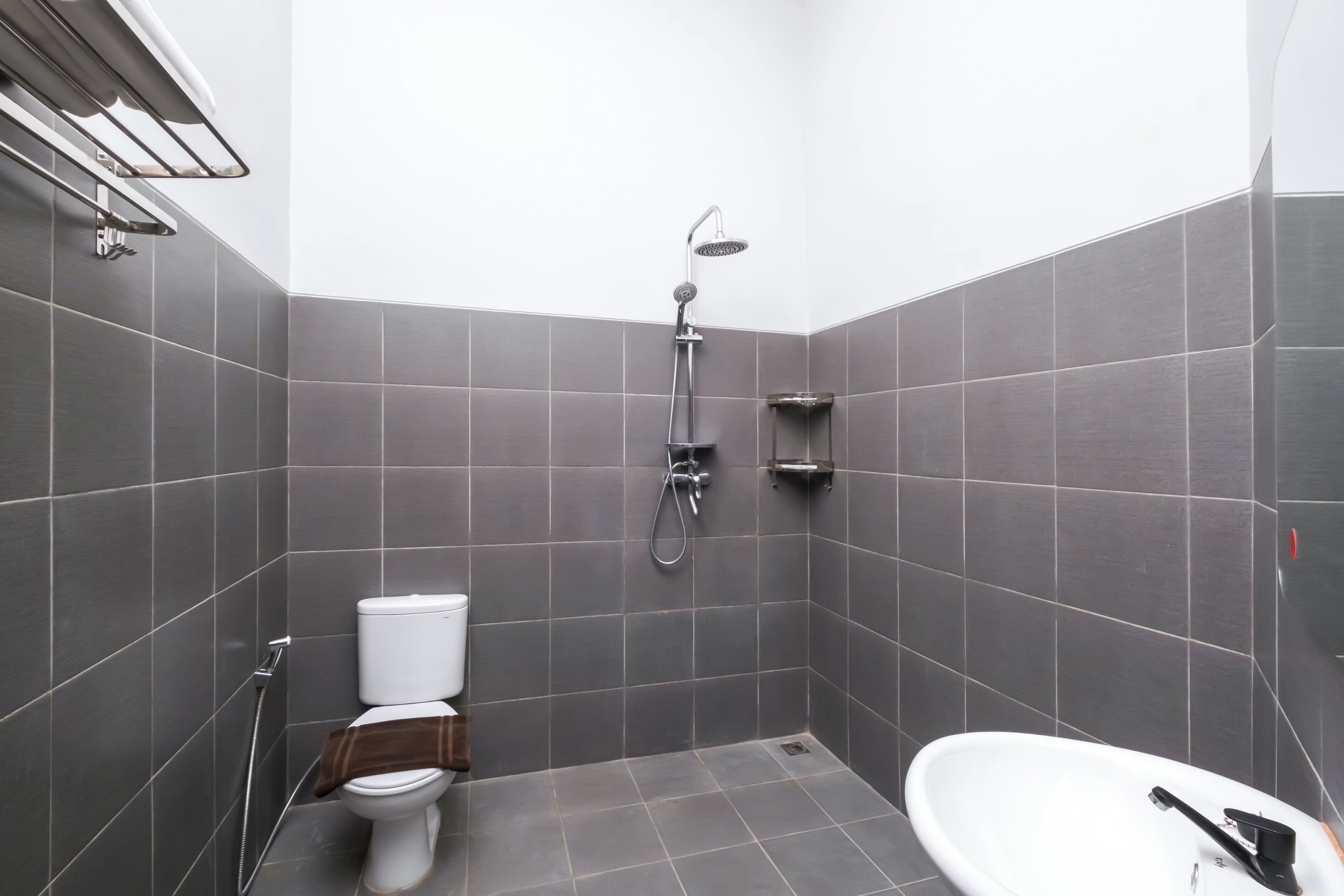 Un baño moderno con ducha, inodoro y un lavabo blanco.