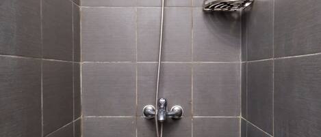 A shower with a handheld showerhead and a wall-mounted faucet in a tiled bathroom.