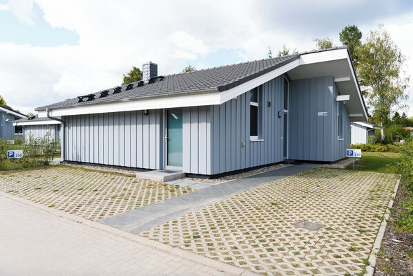 A modern building with a sloped roof, a door, and a window. - Seeschwalbe 330 - The Scandinavian family home for 4 with sauna and whirlpool (Mirow)