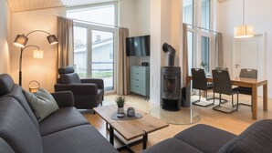 Una sala de estar moderna con un sofá, sillas, una mesa de comedor y una chimenea.