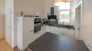 Una cocina moderna con armarios blancos, una isla grande y una lámpara colgante.
