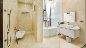 Ein modernes Badezimmer mit einer gläsernen Duschkabine, einer freistehenden Badewanne und einem Waschtisch mit Spiegel.