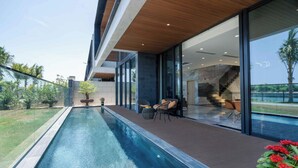 Ein moderner Poolbereich im Freien mit Glasverkleidung, Sitzgelegenheiten und Blick auf die umliegende Landschaft.