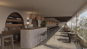 A modern bar area with a long counter, multiple hanging lights, and a row of bar stools. - Elion Seaside by Anayia All Inclusive Resorts (Chalcis)