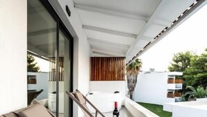 A balcony with a lounge chair, a small table with a bottle of wine, and a glass. - Elion Seaside by Anayia All Inclusive Resorts (Chalcis)