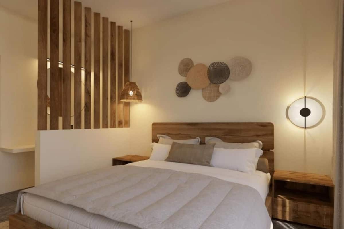 Un dormitorio moderno con una cama grande, cabecera de madera y una lámpara fijada a la pared.