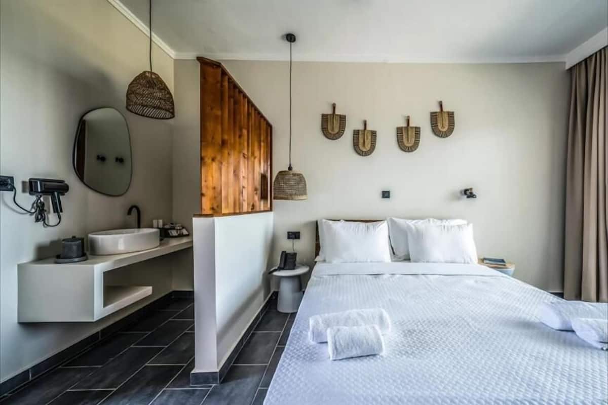Una habitación de hotel moderna con una cama grande, tocador integrado, lámpara colgante y obras de arte en la pared.