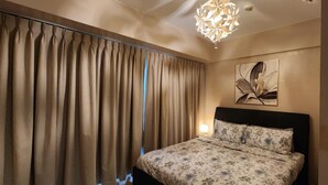 A bedroom with a bed, curtains, a wall-mounted light, and a ceiling light fixture. - 1 Bed Apartment - Sleeps 7 - Pool & Wifi (Pasay)