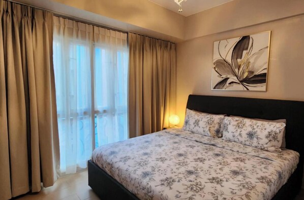 Ein Schlafzimmer mit Bett, Vorhängen, einer Wandleuchte und einem Blumenbild.