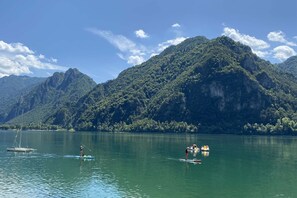 A calm lake with paddle boats and a mountainous backdrop. - Directly on the lake with terrace (Tre Capitelli)