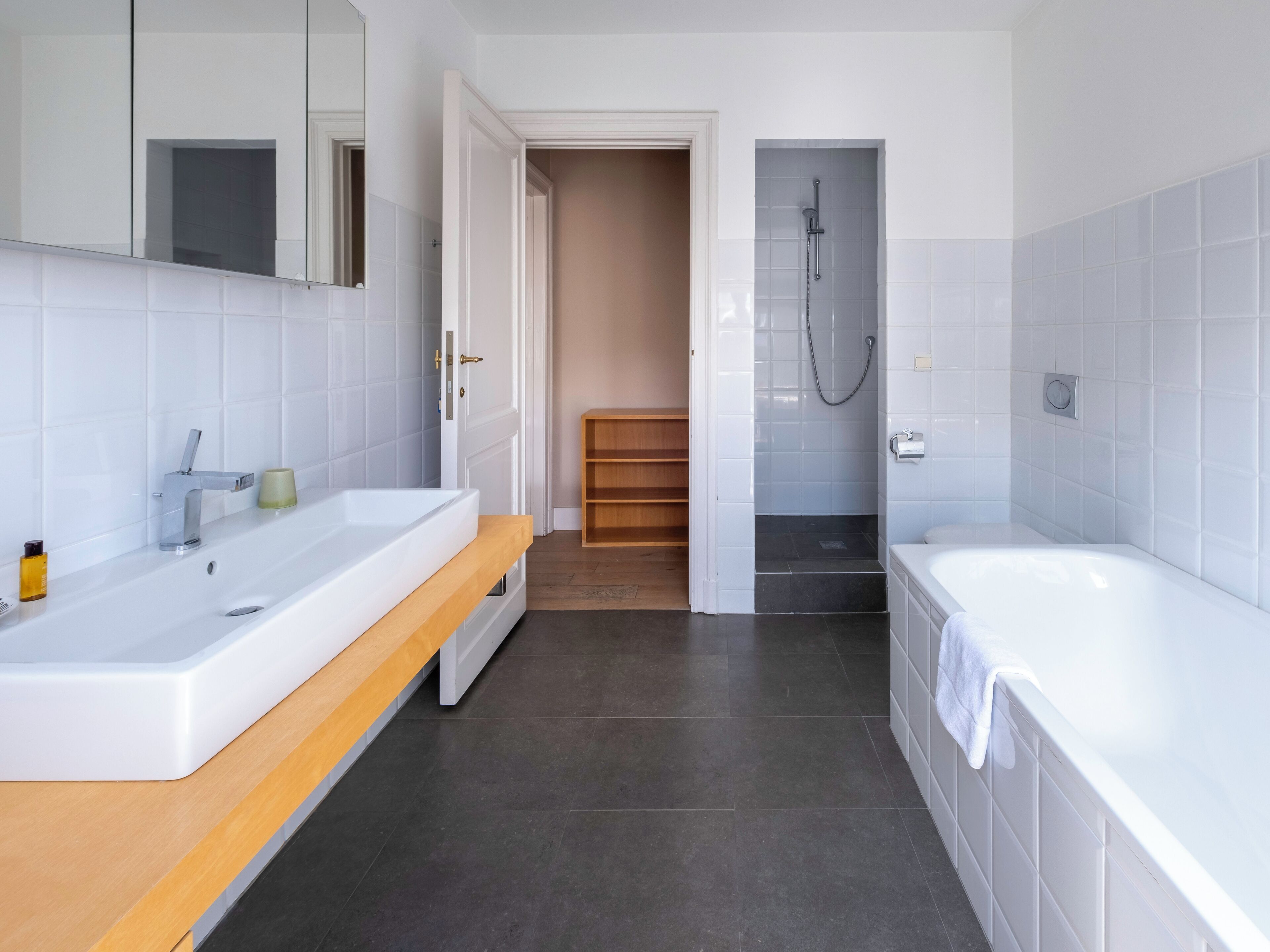 Een moderne badkamer met een groot wit wastafelmeubel, een bad en een douchecabine.