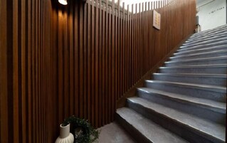 Una escalera con paneles de madera en las paredes y un jarrón blanco con plantas al pie.