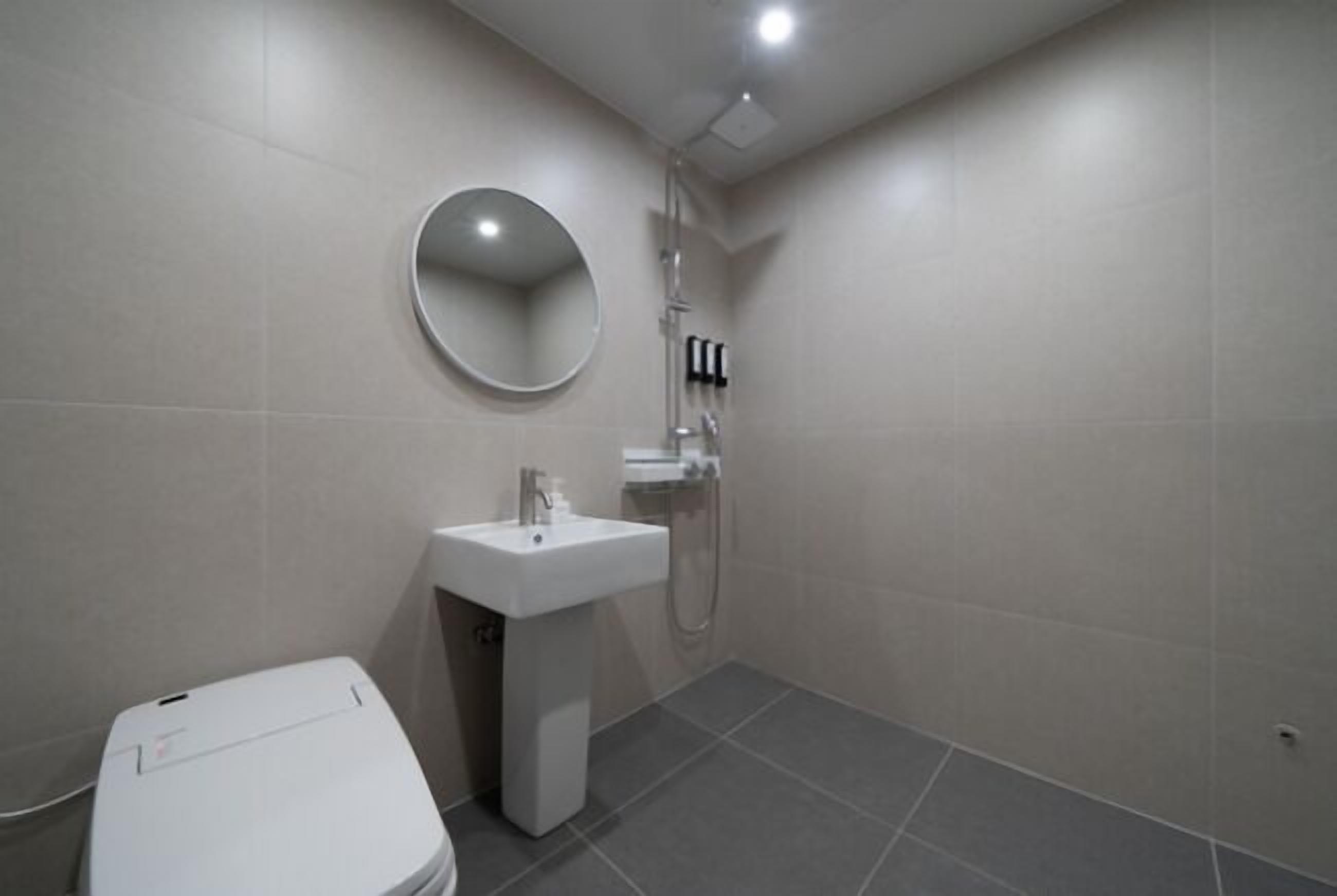 Een moderne badkamer met toilet, wastafel en douche.