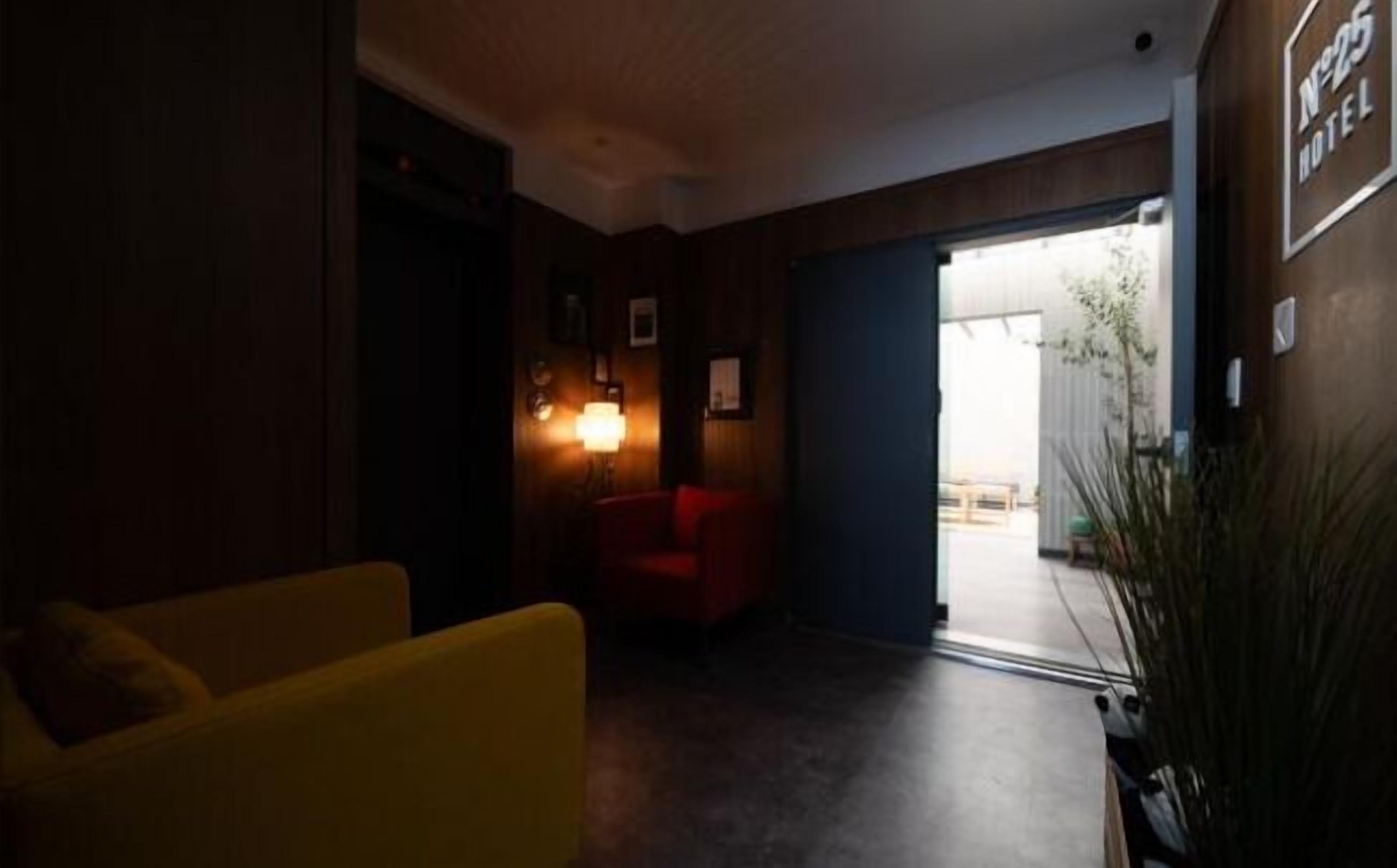 A hotel lobby with a red armchair, a yellow sofa, and a large potted plant.
