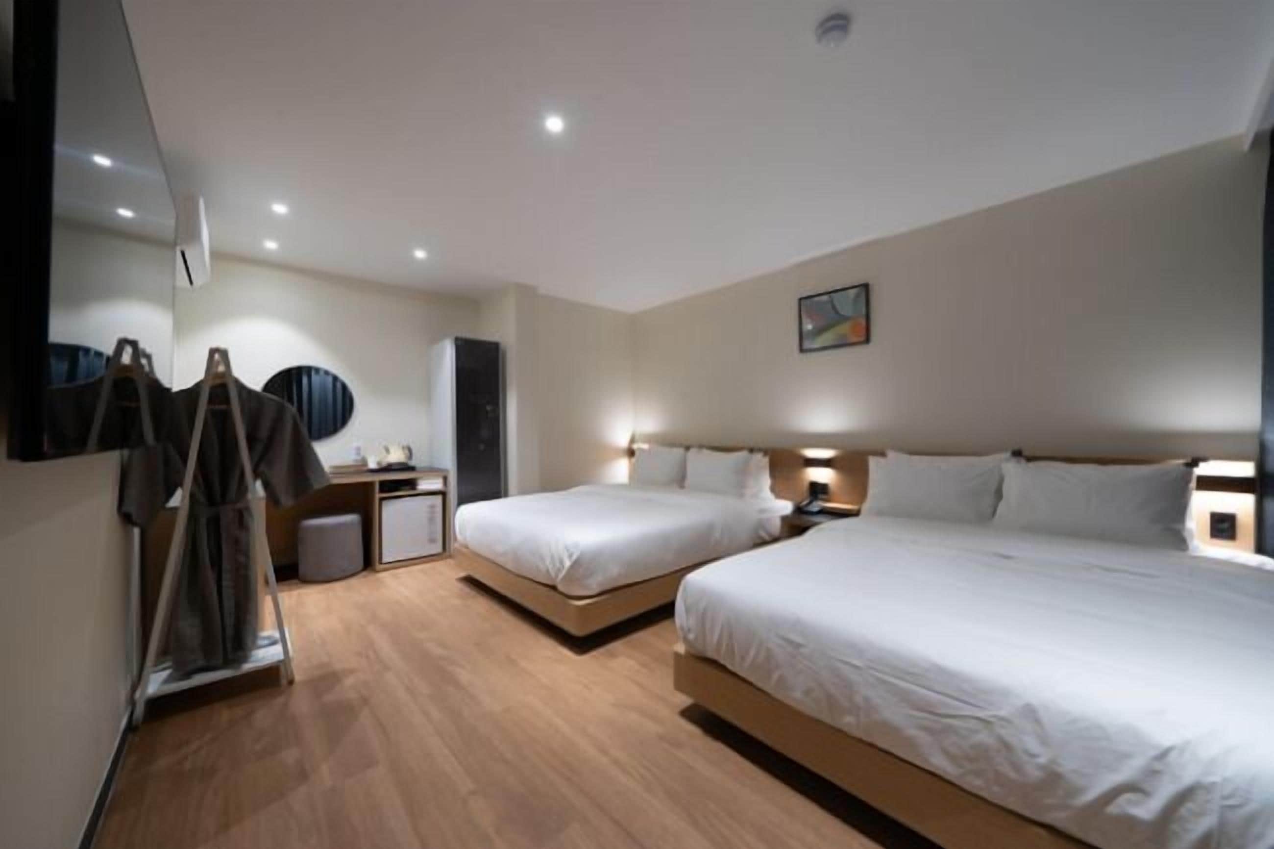 A hotel room with two beds, a wardrobe, a desk, and a mirror.