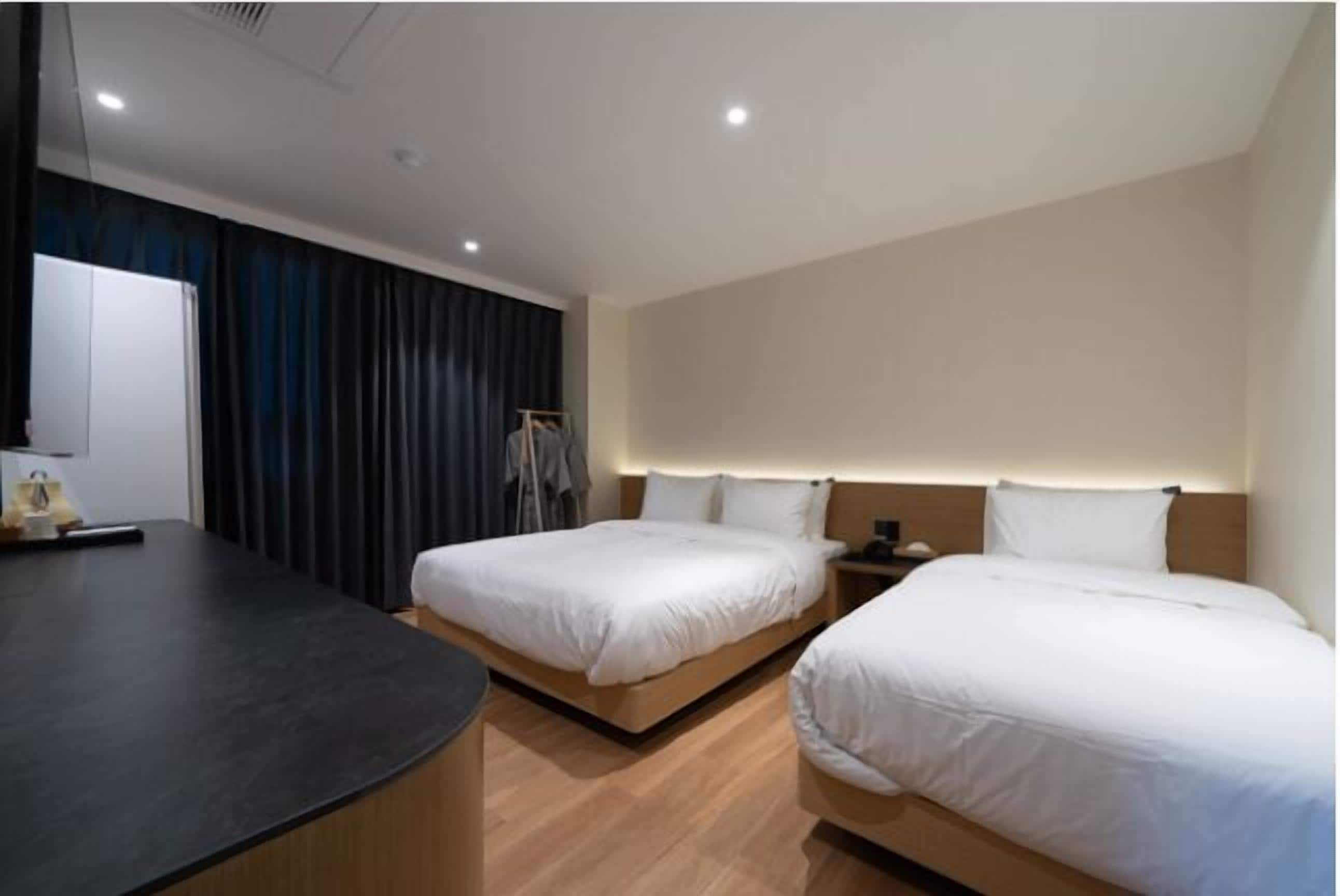 A hotel room with two beds, a desk, and a wardrobe.