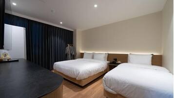A hotel room with two beds, a desk, and a wardrobe.