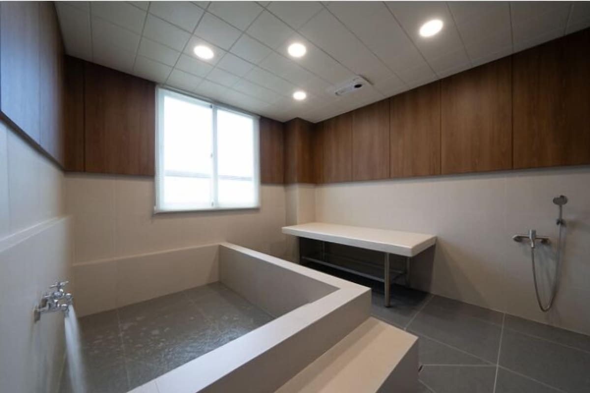 A modern bathroom with a bathtub, a shower, and a window providing natural light.