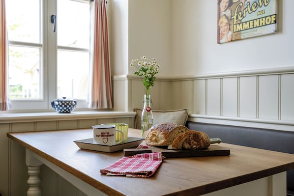 Una escena de desayuno con una hogaza de pan, una taza y un jarrón de flores sobre una mesa de madera.