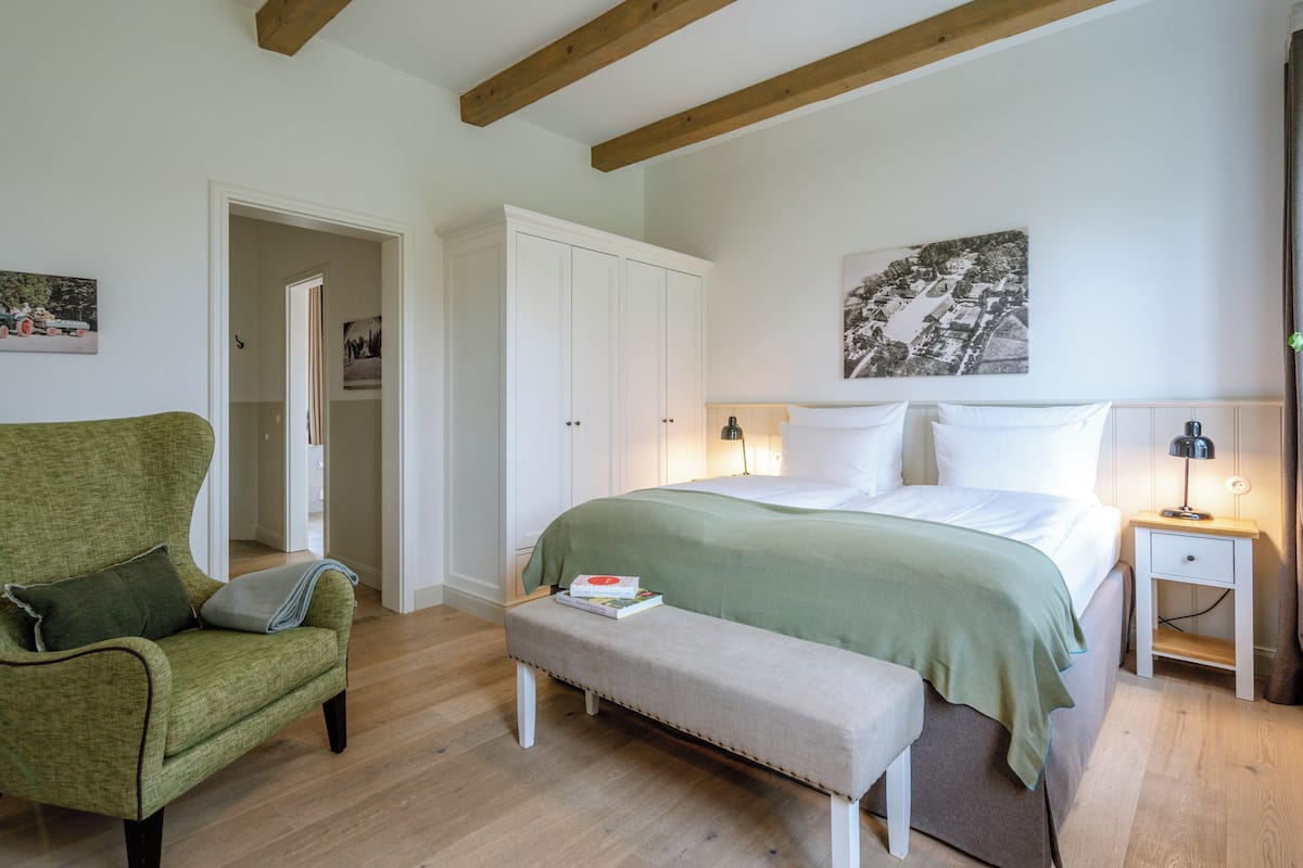 A bedroom with a bed, a bench, a chair, a bedside table, and a wardrobe.