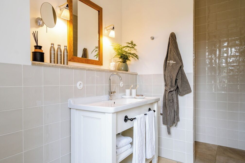 Un baño moderno con lavamanos blanco, espejo y barra para toallas.