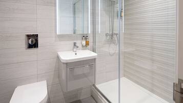 A modern bathroom with a toilet, sink, and glass-enclosed shower.