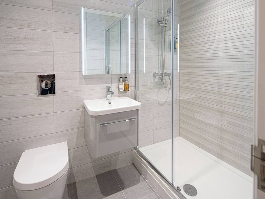 A modern bathroom with a toilet, sink, and glass-enclosed shower.