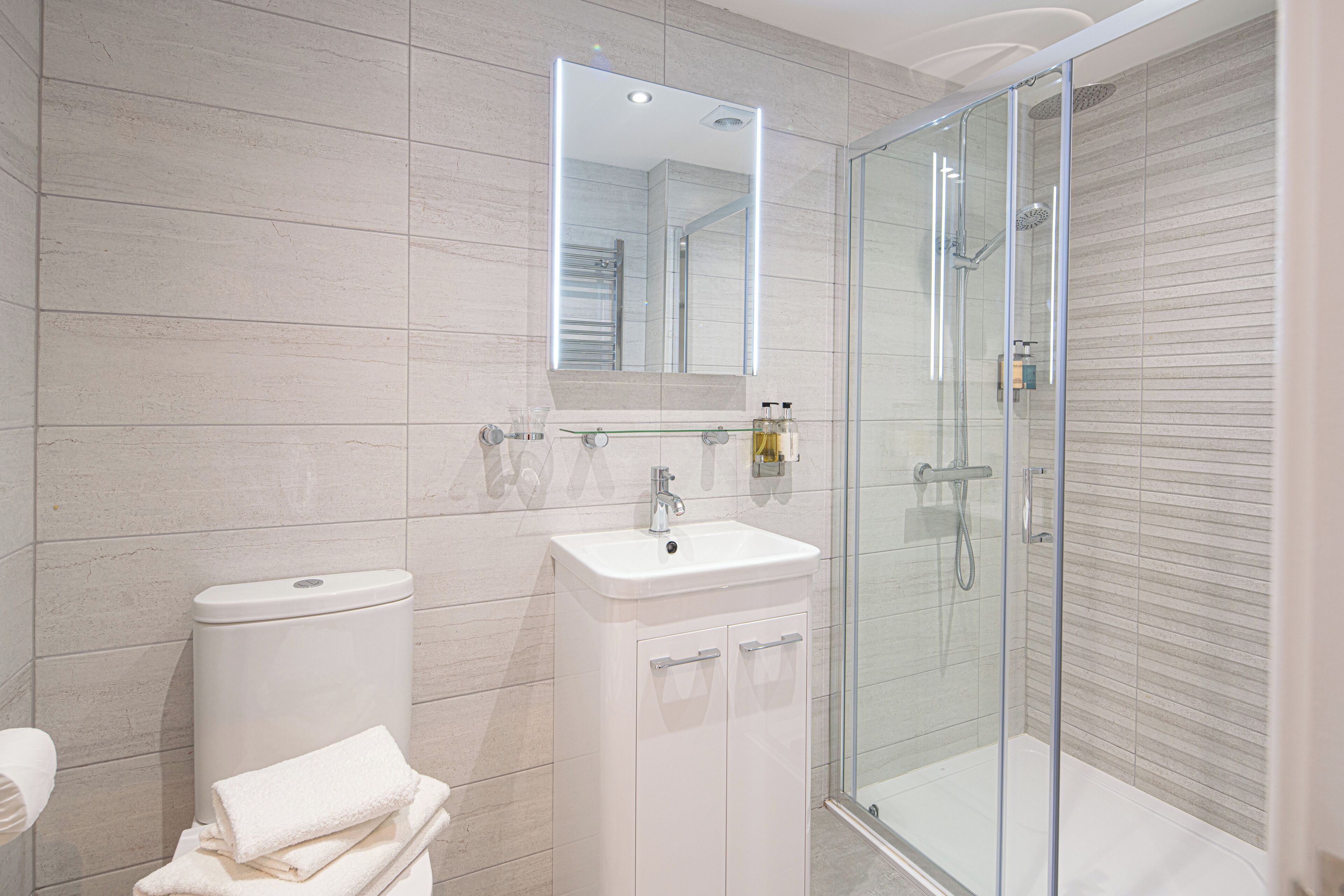 A modern bathroom with a glass-enclosed shower, a white sink, and a toilet.