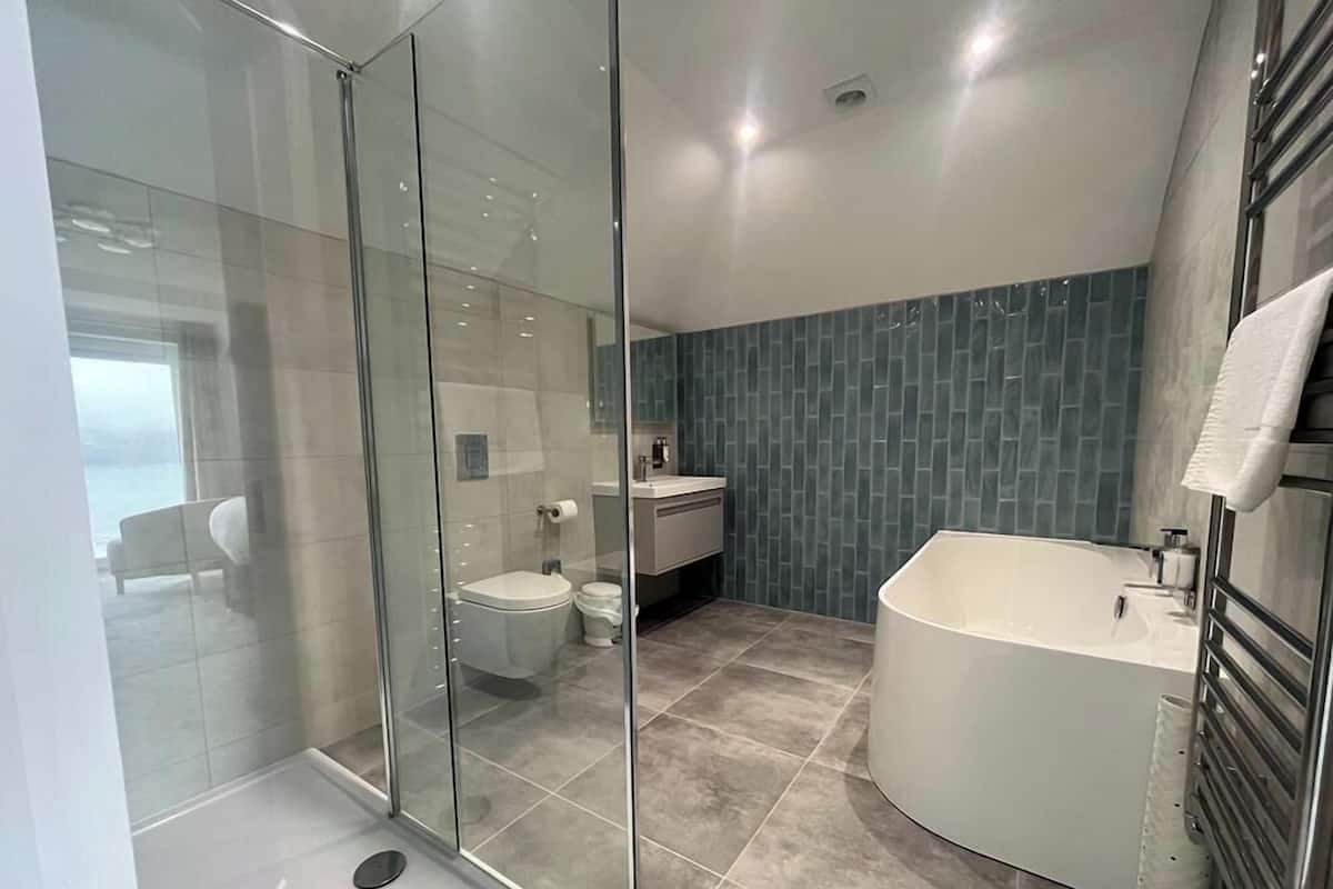 Ein modernes Badezimmer mit Duschkabine aus Glas, einer freistehenden Badewanne und einem separaten WC.