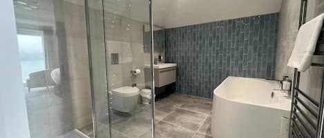 A modern bathroom with a glass shower enclosure, a freestanding bathtub, and a separate toilet.