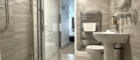 Un baño moderno con cabina de ducha de vidrio, un lavabo blanco y un espejo sobre él.