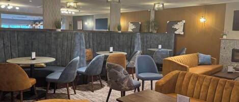 A modern interior with seating arrangements, tables, and decorative lighting.