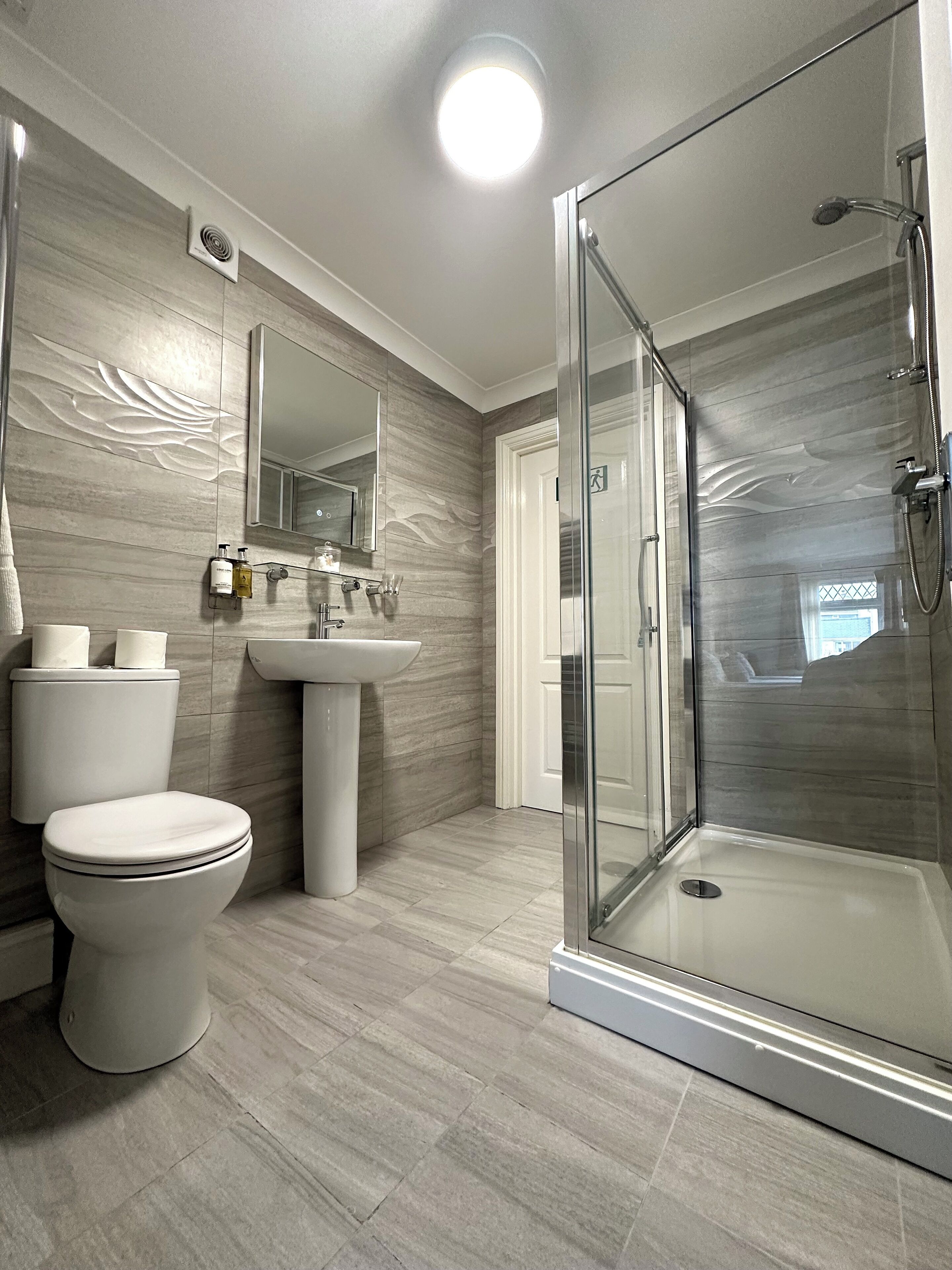 A modern bathroom with a toilet, sink, and glass-enclosed shower.