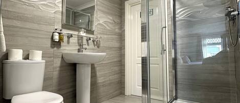 A modern bathroom with a toilet, sink, and glass-enclosed shower.