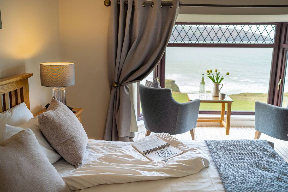 Ein Hotelzimmer mit Bett, Schreibtisch und Blick aufs Meer.