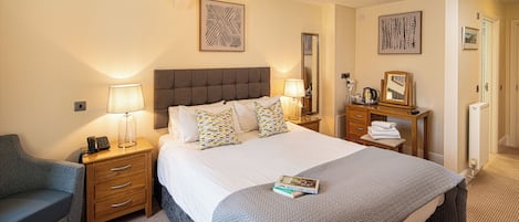 A hotel room with a large bed, bedside tables, a desk, and a chair.