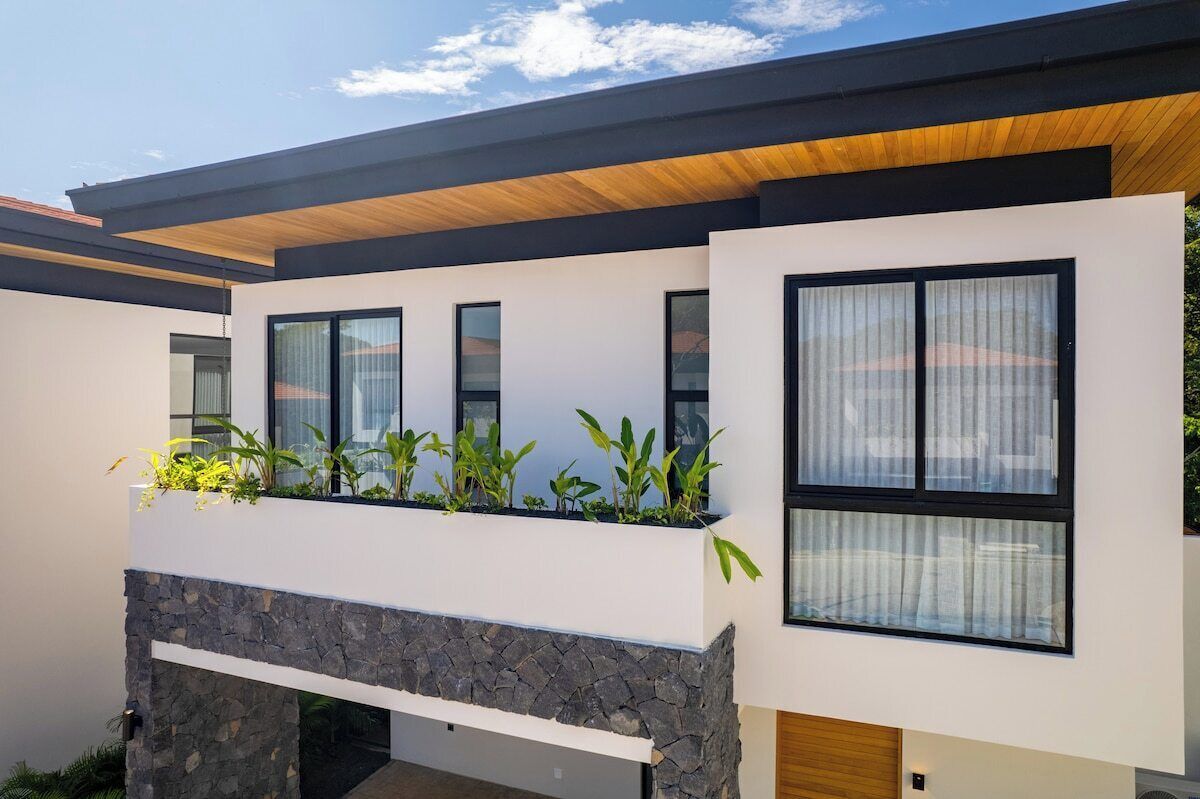 Un edificio moderno con techo plano, ventanas amplias y base de piedra.