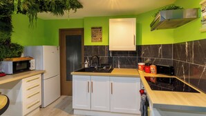 Une cuisine avec un mur vert, des armoires blanches, un plan de travail noir et un four à micro-ondes.