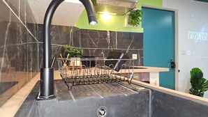 Une cuisine moderne avec un évier noir, un égouttoir et un mur vert avec une porte.