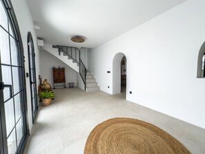 A spacious interior with a staircase, a wooden cabinet, and a potted plant. - Casa Gina Old Town Marbella Center 4 Bedrooms (Marbella)