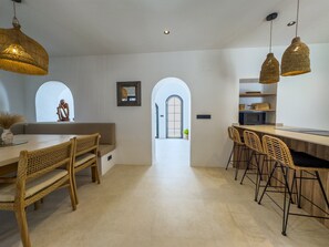 Moderni keittiö, jossa on keskeinen saareke, baarituolit ja näkymä ruokailutilaan.
