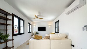A modern living room with a white sofa, a ceiling fan, and a TV mounted on the wall. - Casa Gina Old Town Marbella Center 4 Bedrooms (Marbella)